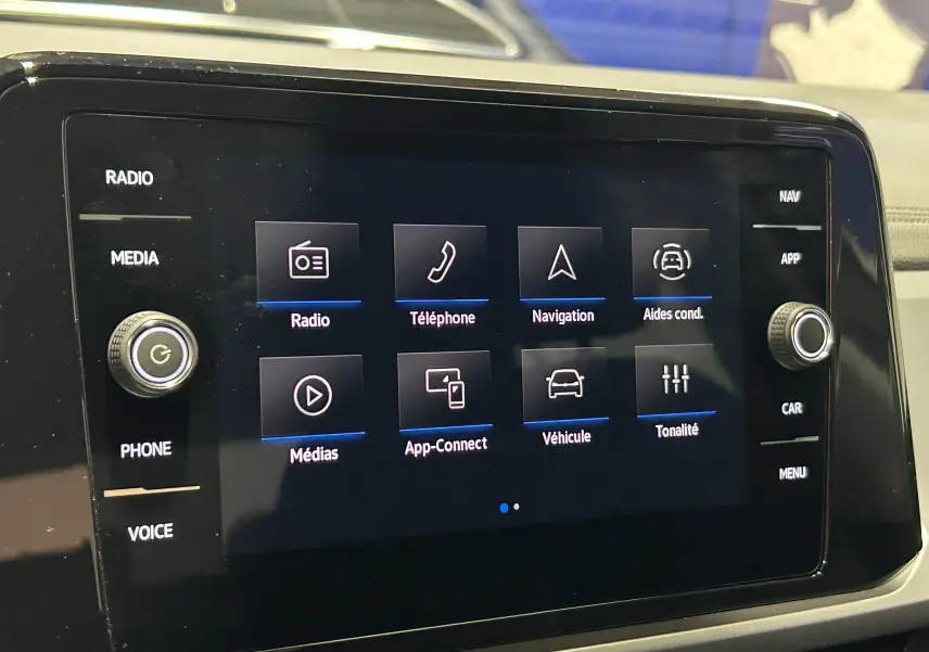 Écran tactile central du Volkswagen T-Roc 2025 affichant les options radio, téléphone, navigation et aides à la conduite.