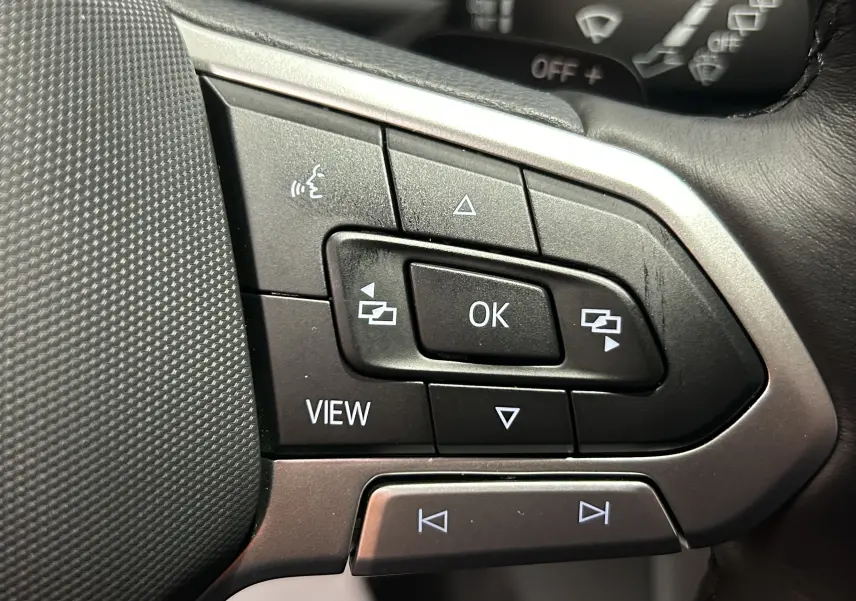 Gros plan sur les commandes multifonctions noires et argent du volant du Volkswagen T-Roc TSI 150 DSG Life 2025.