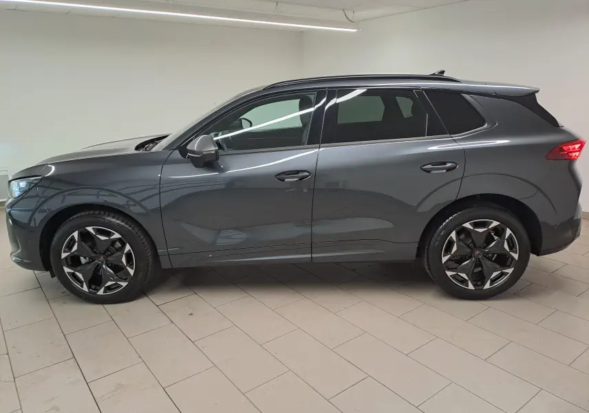 Vue de profil côté gauche d'un CUPRA TERRAMAR gris Timanfaya avec jantes 19'' Cosmic usinées dans un intérieur lumineux.