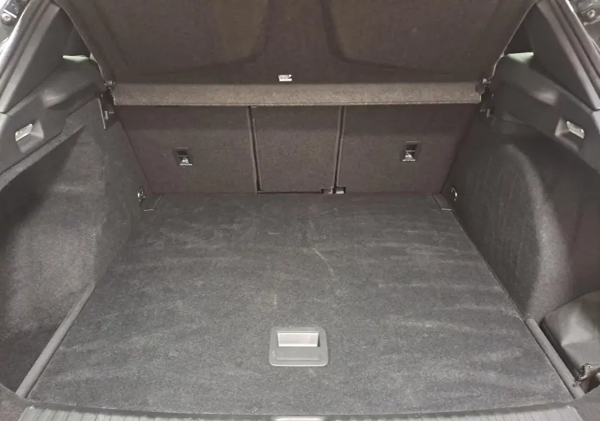 Coffre ouvert vu de l'arrière d'une CUPRA TERRAMAR 1.5 eTSI gris Timanfaya, espace de chargement vide et tapis noir.
