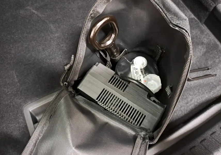 Gros plan sur le kit de secours dans le coffre du CUPRA TERRAMAR 2025, avec pochette noire ouverte et outils visibles.