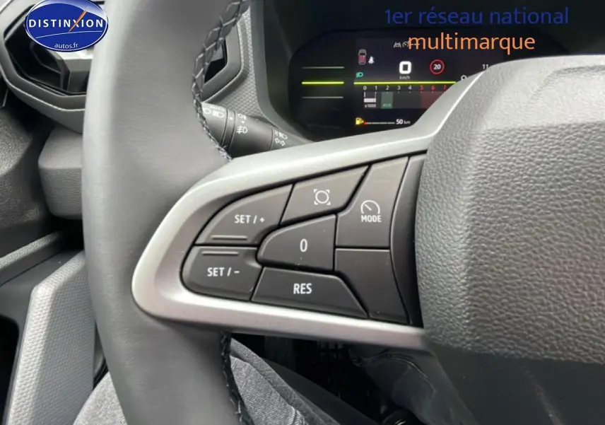 Gros plan sur les commandes au volant à gauche du Dacia Duster 2026, avec affichage numérique du tableau de bord en arrière-plan.