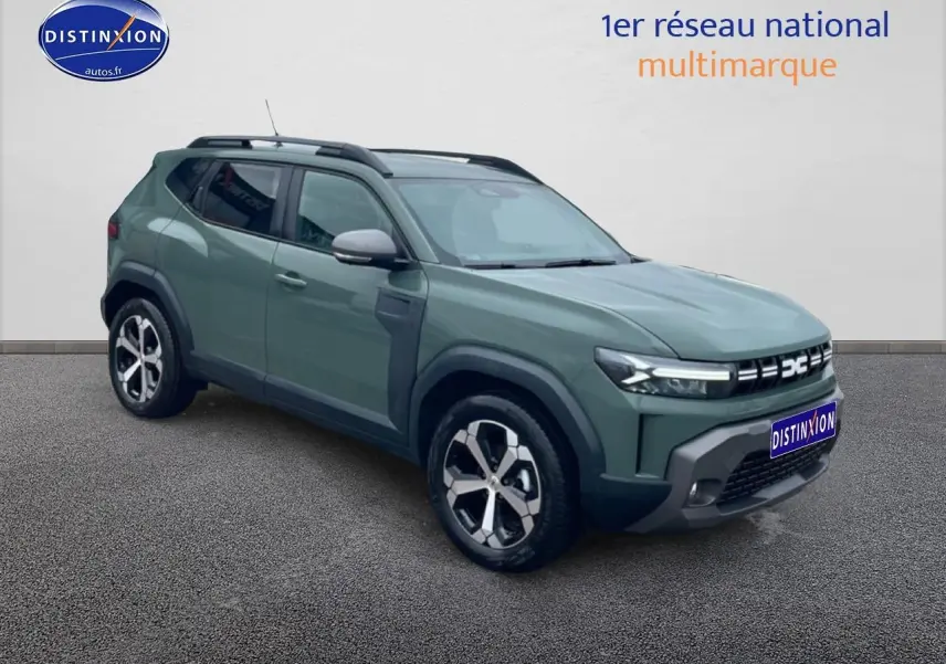 Dacia Duster vert kaki en 3/4 avant droit, avec jantes alu et barres de toit noires visibles.