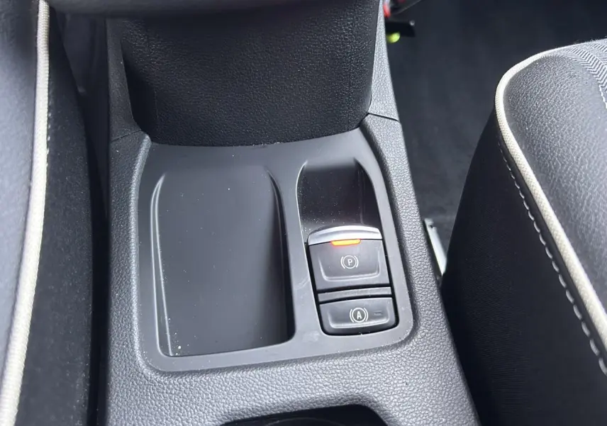 Gros plan sur la console centrale avant de la Renault Clio V TCE 90 Techno noire, avec frein de parking électrique activé.