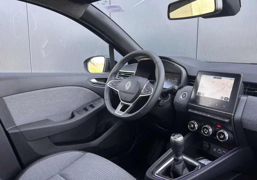 Vue intérieure côté conducteur de la Renault Clio 2025 noir étoilé avec volant multifonction et écran tactile central.