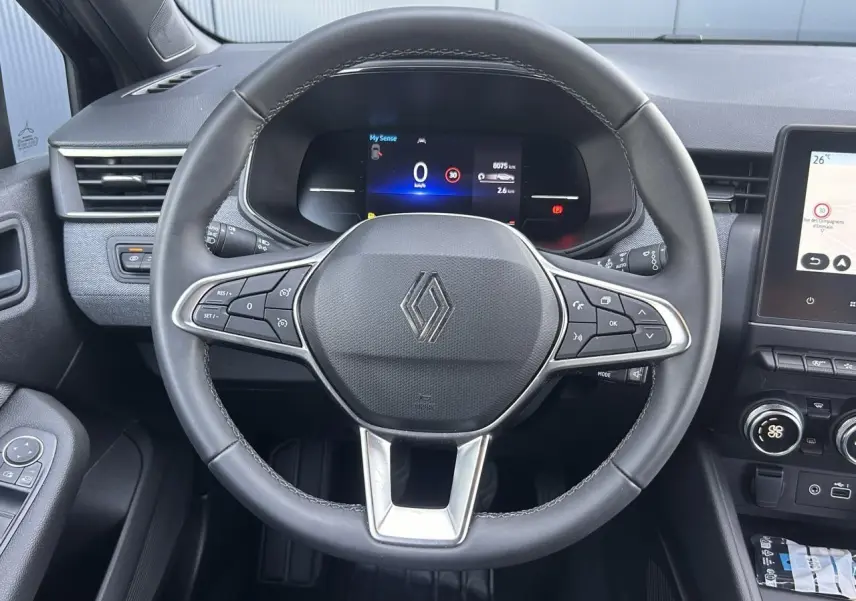 Vue rapprochée du volant multifonction noir de la Renault Clio 2025 avec tableau de bord numérique et écran tactile.