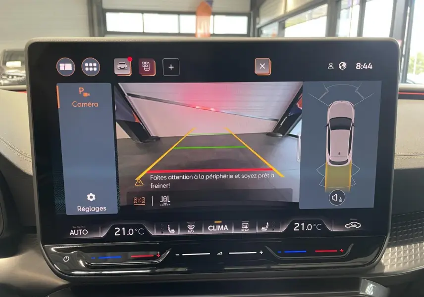 Écran tactile intérieur affichant la caméra de recul et l'aide au stationnement du CUPRA Leon noir.