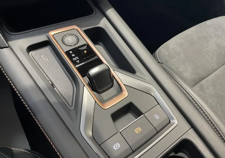 Gros plan sur la console centrale de la CUPRA Leon 2.0 TDI noire, avec levier de vitesse DSG et surpiqûres cuivrées.