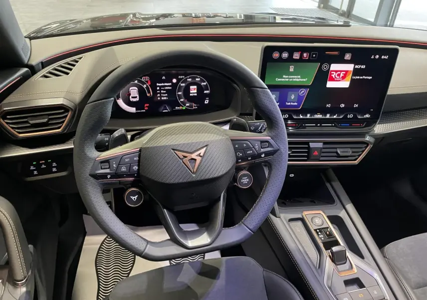 Vue intérieure frontale du poste de conduite du CUPRA Leon noir avec volant multifonctions et écran tactile HD.