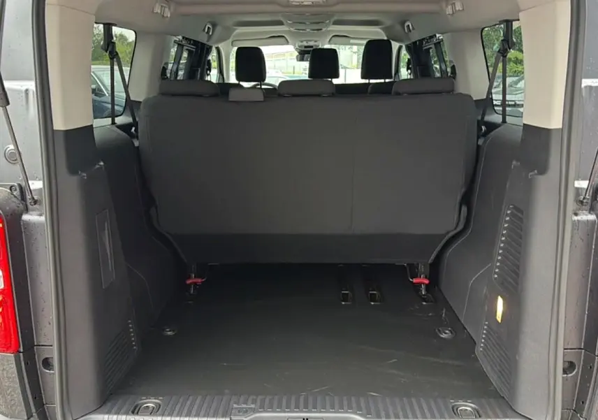 Vue arrière du coffre ouvert du FIAT Scudo Combi gris titane, montrant la banquette arrière et l’espace de chargement.