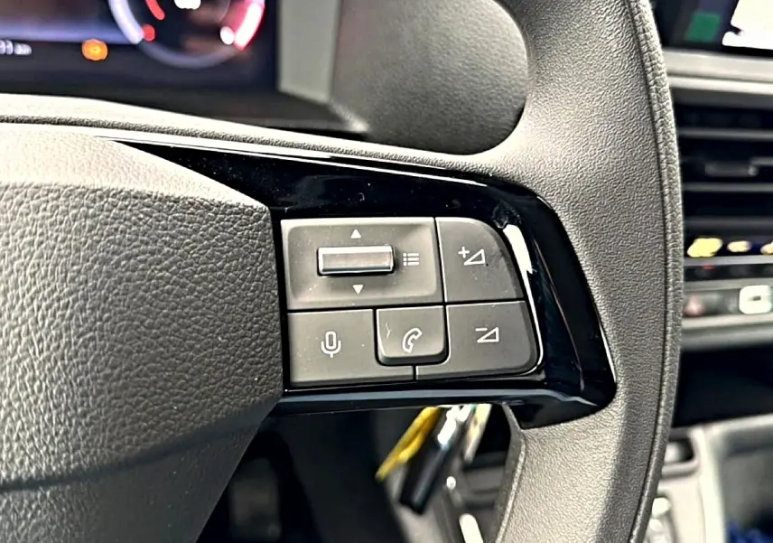 Gros plan sur les commandes au volant noir du Fiat Scudo Combi gris titane, avec écran multifonction en arrière-plan.