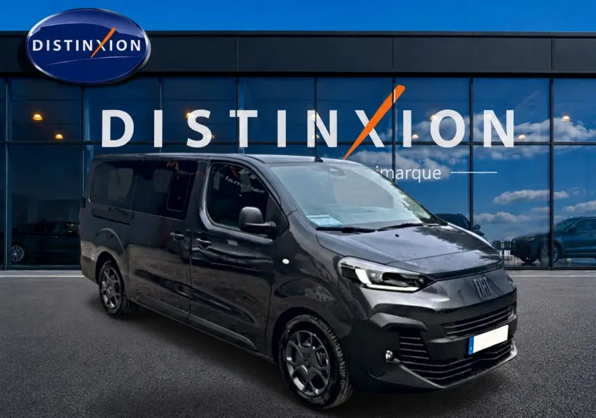 Fiat Scudo Combi gris titane en 3/4 avant droit, porte latérale coulissante visible, devant vitrine Distinxion.