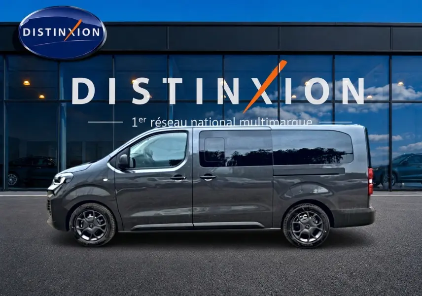 Profil droit du FIAT Scudo Combi gris titane avec porte latérale coulissante, stationné devant une vitrine Distinxion.