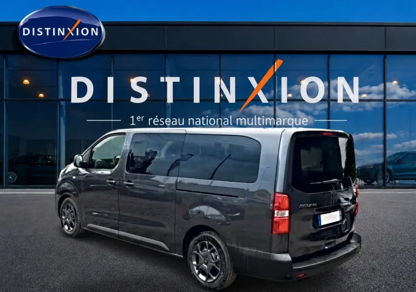 Vue 3/4 arrière droite d'un FIAT Scudo Combi gris titane avec porte latérale coulissante, stationné devant un showroom Distinxion.