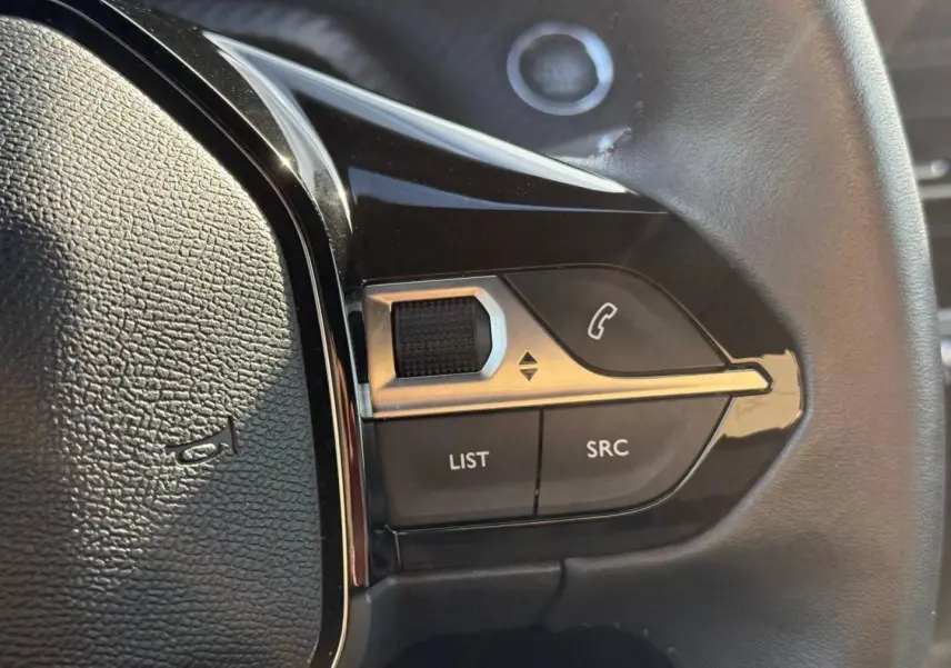 Gros plan sur les commandes gauche du volant noir du Peugeot e-2008 2025 avec boutons téléphone et réglages audio.