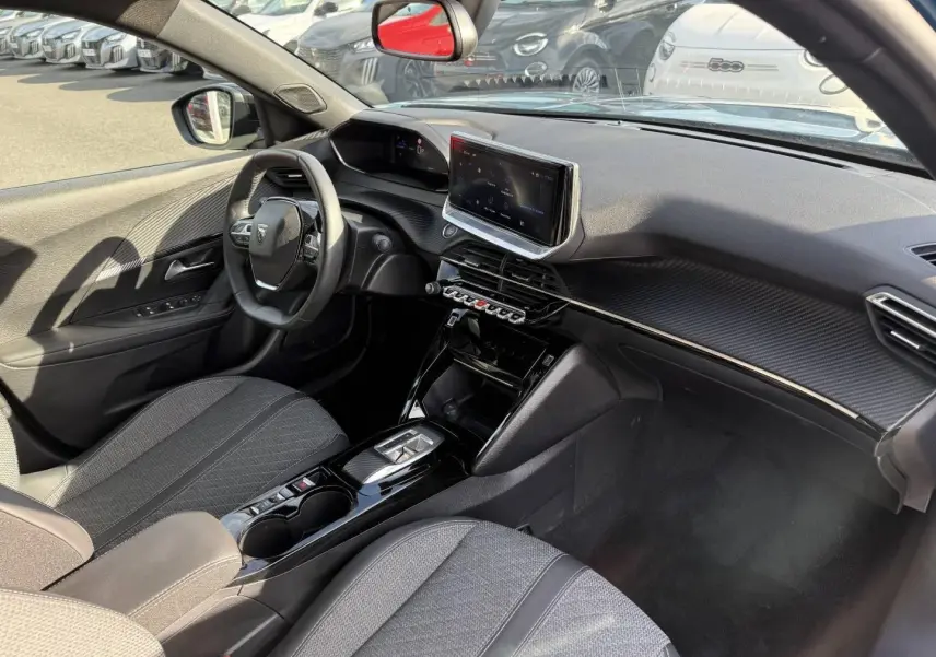 Vue intérieure côté conducteur du Peugeot e-2008 2025, avec tableau de bord noir et écran tactile central.