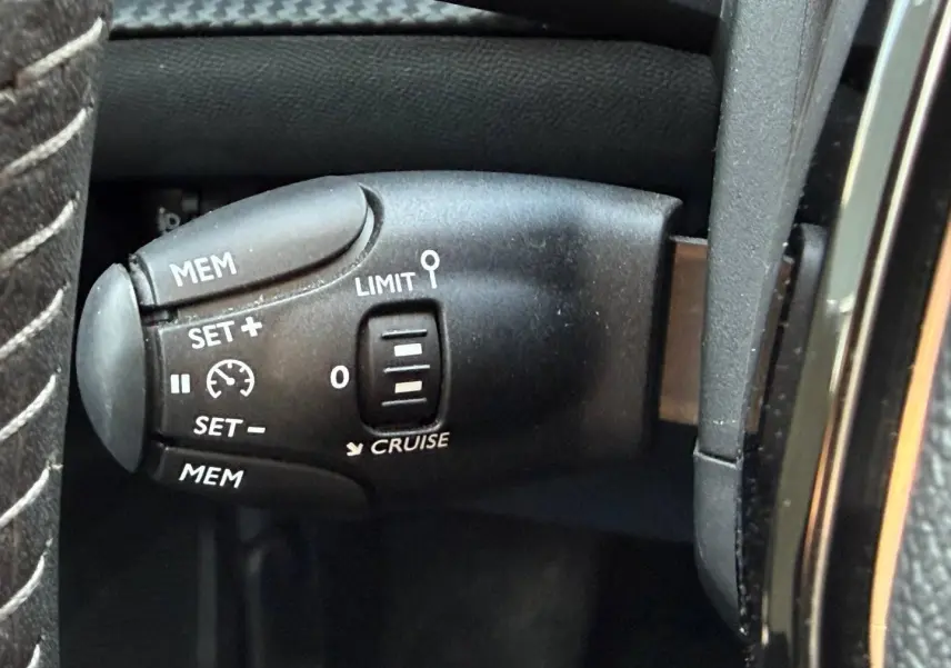 Gros plan sur la commande de régulateur de vitesse au volant d'un Peugeot e-2008 bleu Obsession.