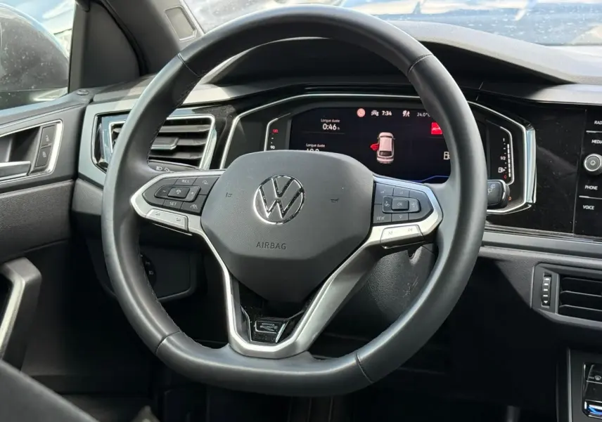 Vue rapprochée du volant cuir multifonction noir du Volkswagen Taigo 2025 avec tableau de bord digital en arrière-plan.