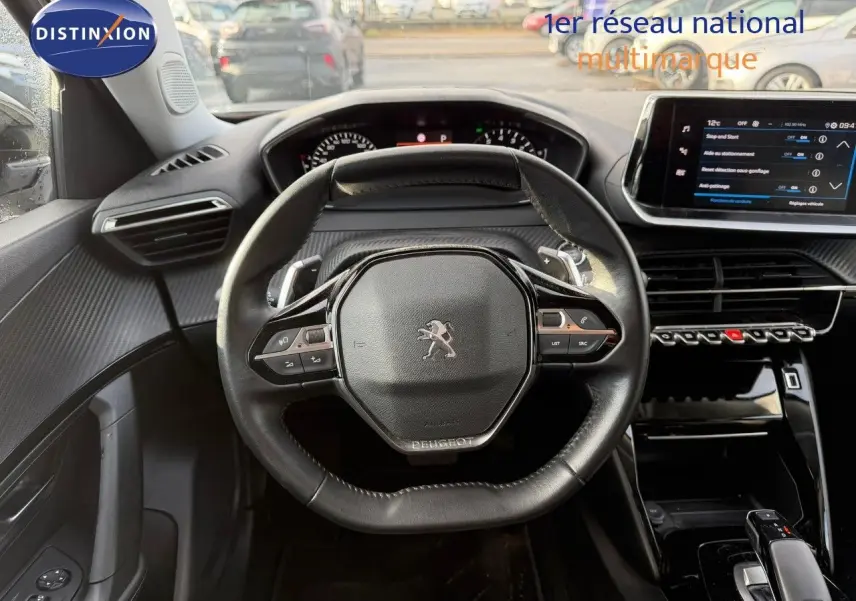 Vue intérieure centrée sur le volant cuir noir et le tableau de bord numérique du Peugeot 2008 gris Artense 2022.