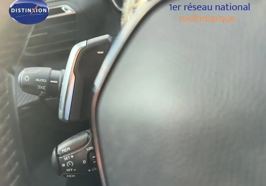 Détail du volant et des commandes de régulateur de vitesse d’un Peugeot 2008 gris Artense, intérieur noir.