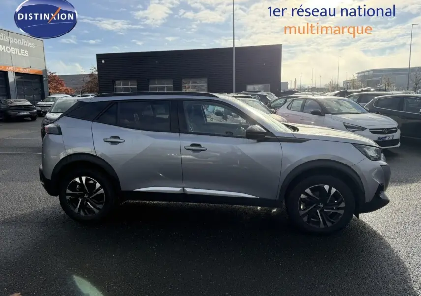 Profil droit d'un Peugeot 2008 gris Artense 2022 avec jantes noires et toit noir, stationné en extérieur par temps ensoleillé.