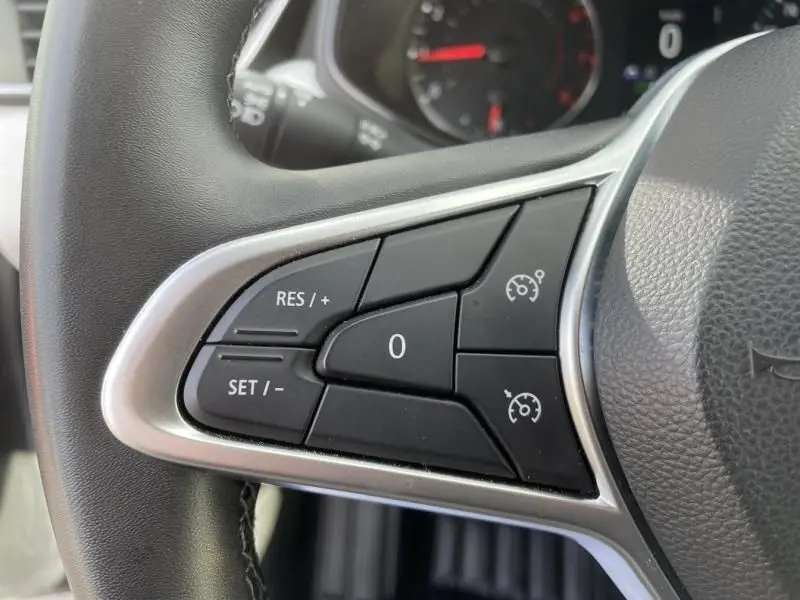 Gros plan sur les commandes de régulateur de vitesse au volant d'une Renault Clio V gris foncé métal 2023.