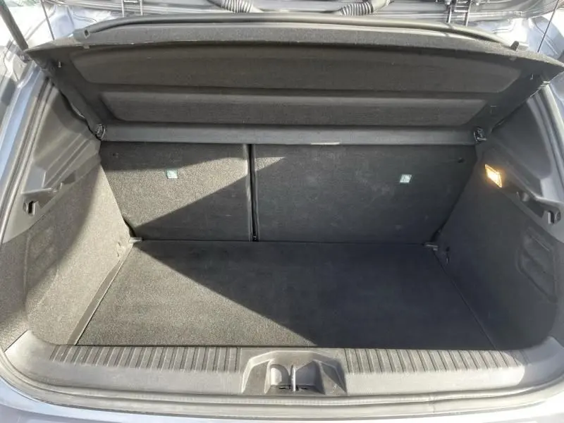 Coffre ouvert vu de l'arrière d'une Renault Clio V TCE 90 X-TRONIC Evolution 2023 gris foncé métal, espace de chargement vide.