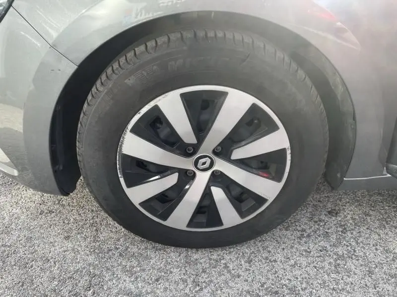 Gros plan sur la roue avant gauche d'une Renault Clio V gris foncé métal avec jante alliage au design moderne.