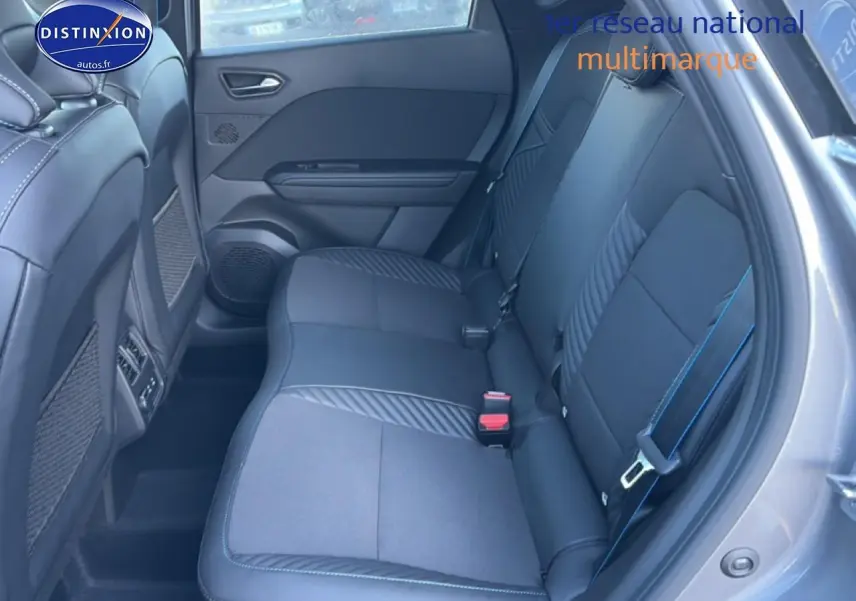 Vue intérieure côté droit montrant la banquette arrière noire avec surpiqûres bleues du Renault Captur hybride 2025.