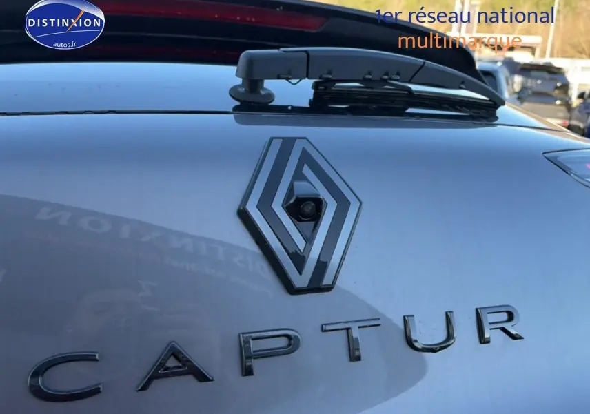 Gros plan sur le logo Renault et l'inscription Captur sur la partie arrière gris cassiopée du véhicule.