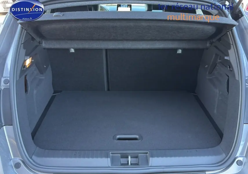 Coffre ouvert vu de l'arrière d'un Renault Captur gris cassiopée, montrant un espace de chargement propre et vide.