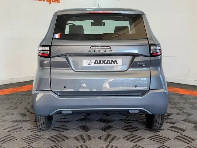 Vue arrière d'une Aixam Ambition 0.5 City Pack gris foncé 2026 avec rétroviseur caméra côté conducteur.
