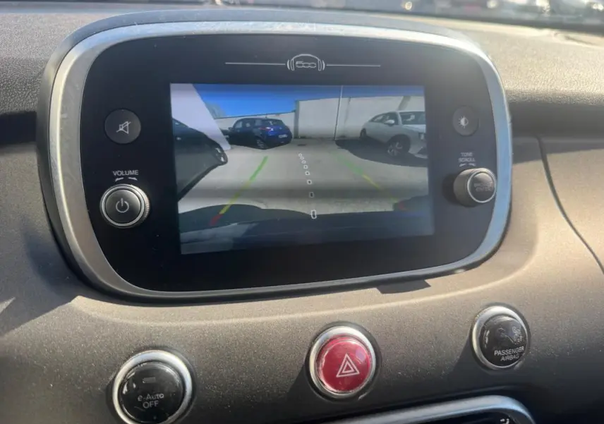 Écran central de la FIAT 500X MY23 montrant la caméra de recul avec vue arrière sur un véhicule bleu.