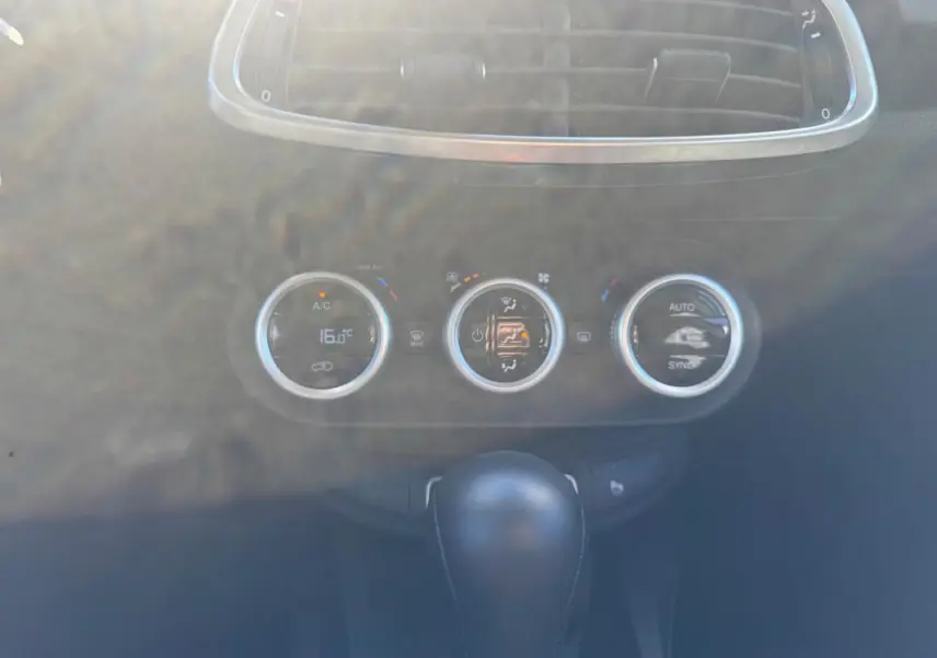 Gros plan sur la console centrale du Fiat 500X bleu MY23, montrant les commandes de climatisation et le levier de vitesse automatique.