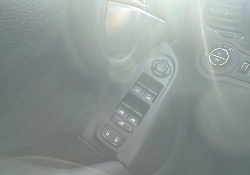 Détail des commandes des vitres électriques et réglage des rétroviseurs sur la porte côté conducteur d’un FIAT 500X bleu.