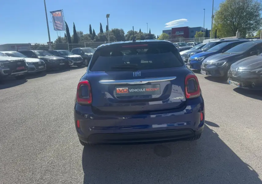 Vue arrière d'une FIAT 500X bleu foncé avec feux arrière distinctifs et badge hybride visible sur un parking.
