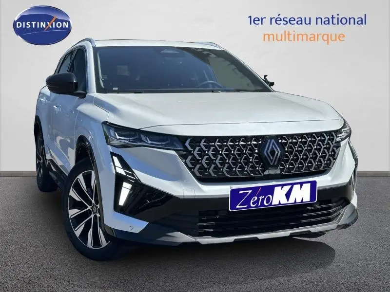 Renault Austral blanc nacré en 3/4 avant droit, avec calandre noire à motif géométrique et feux LED distinctifs.