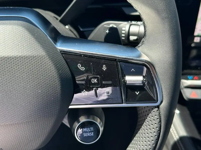 Gros plan sur les commandes multifonctions côté gauche du volant noir du Renault Austral blanc nacré 2025.
