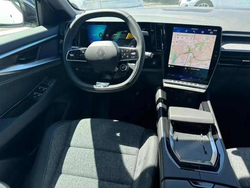 Vue intérieure avant du Renault Austral 2025, volant multifonction et grand écran tactile avec navigation affichée.