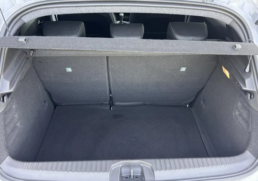 Coffre ouvert de la Renault Clio V TCE 90 Techno gris Rafale, montrant l’espace de chargement vide et les dossiers arrière.