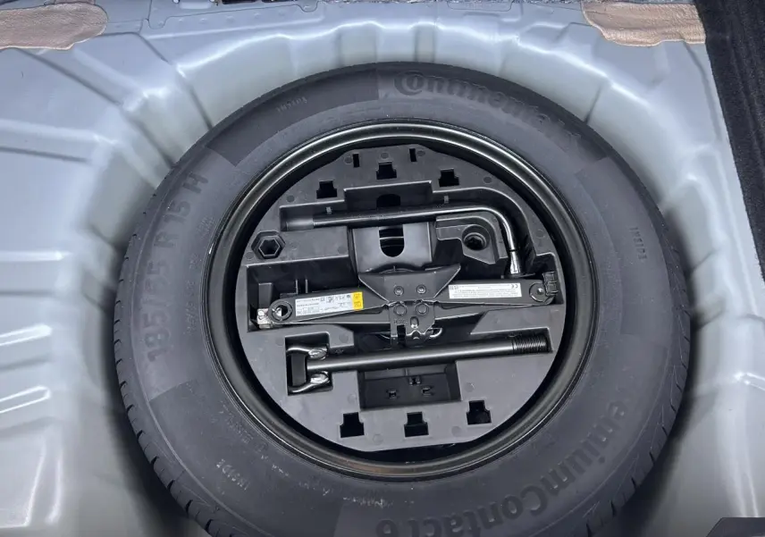 Vue plongeante sur la roue de secours tôle et ses outils dans le coffre de la Renault Clio Gris Rafale 2025.