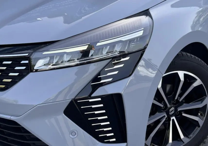 Gros plan sur l'avant droit de la Renault Clio 2025 Gris Rafale, mettant en valeur le phare LED et la jante alliage noire et argent.