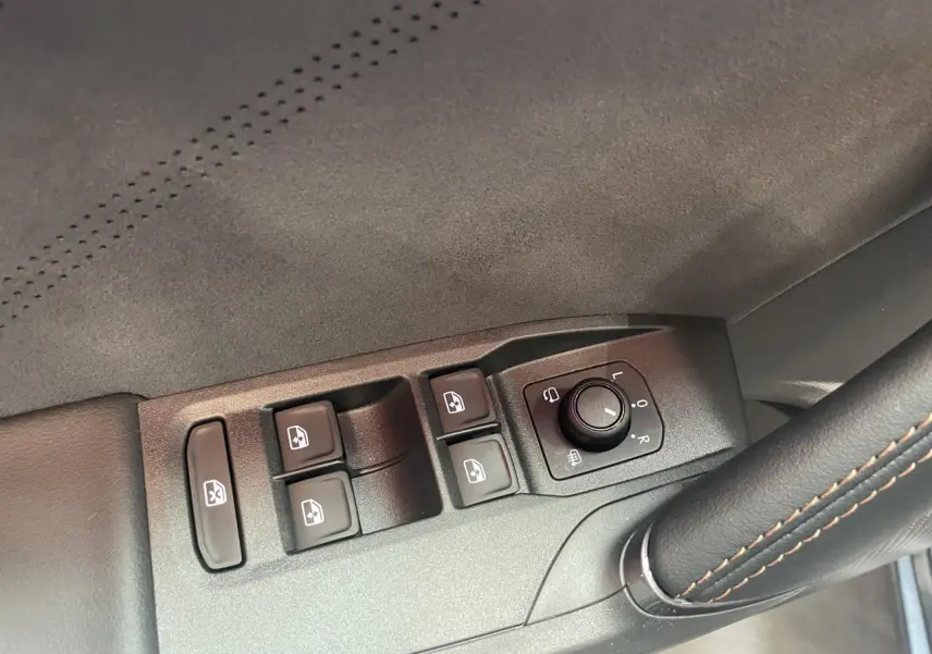 Détail des commandes de lève-vitres et réglage des rétroviseurs sur la porte côté conducteur d’une CUPRA Leon gris.
