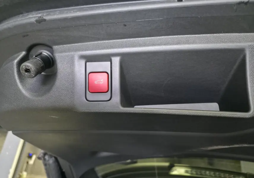 Gros plan sur le bouton rouge d'ouverture motorisée du hayon du coffre du Peugeot 308 SW noir, intérieur du hayon visible.