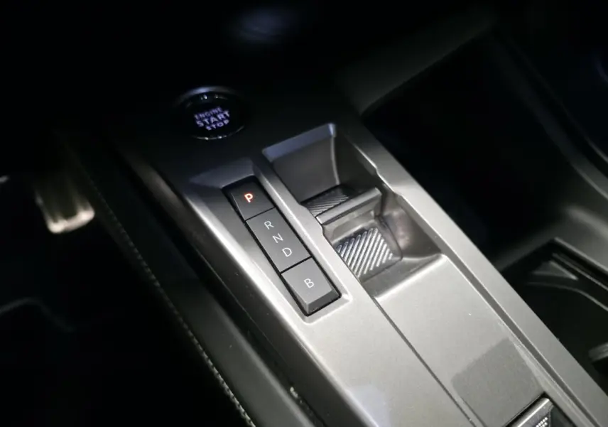 Vue rapprochée de la console centrale grise avec sélecteur de boîte automatique et bouton start/stop dans une Peugeot 308 SW noire.
