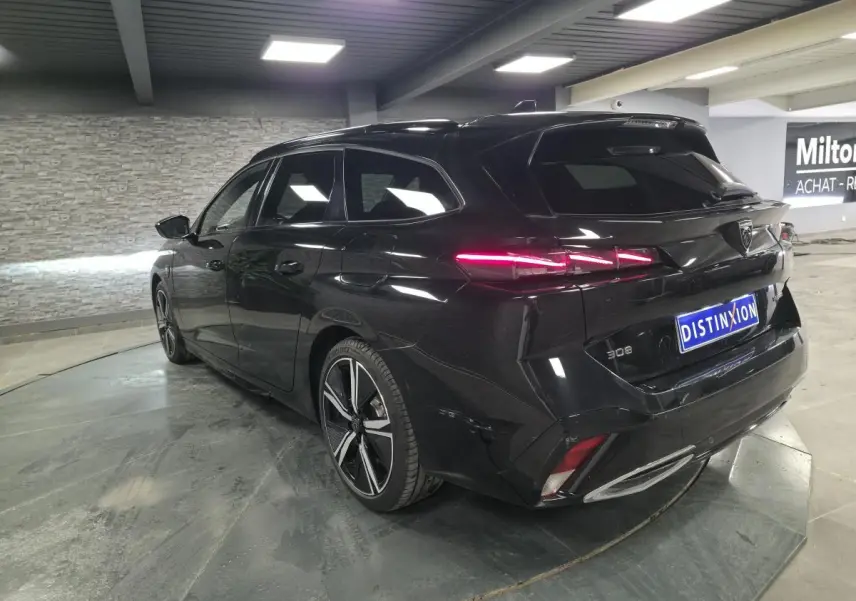 Vue 3/4 arrière droite d'une Peugeot 308 SW noire 2024 avec feux arrière LED et jantes alliage 18 pouces.