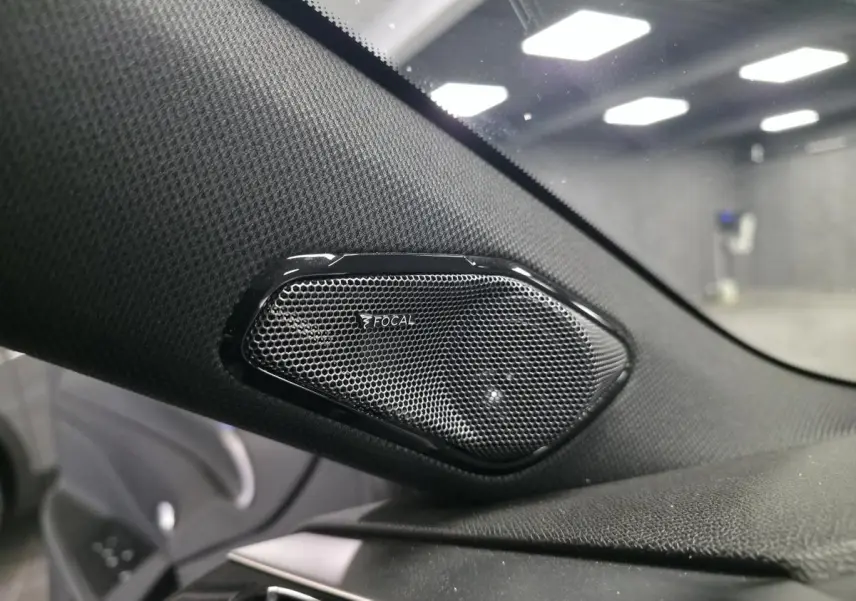 Gros plan sur le haut-parleur Focal noir intégré à la garniture intérieure côté gauche d'une Peugeot 308 SW noire.