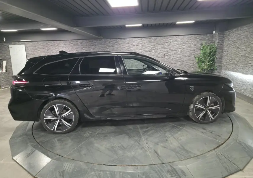 Peugeot 308 SW hybride noire vue de profil côté gauche, jantes alliage noires et toit noir brillant.