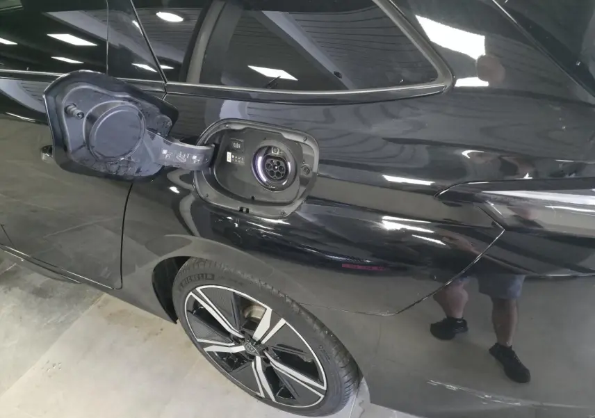 Prise de recharge ouverte côté arrière gauche d’une Peugeot 308 SW noire avec jante alliage 18 pouces.