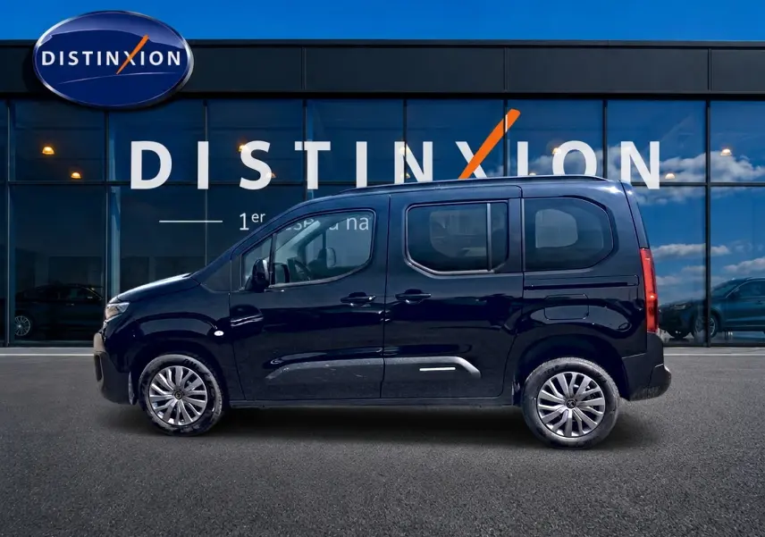 Vue de profil côté gauche d'un Citroën Berlingo noir 2026 devant une vitrine avec logo Distinxion.